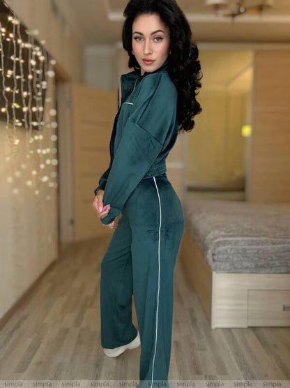 Woman in teal tracksuit standing in a room with decorative lights on the wall.