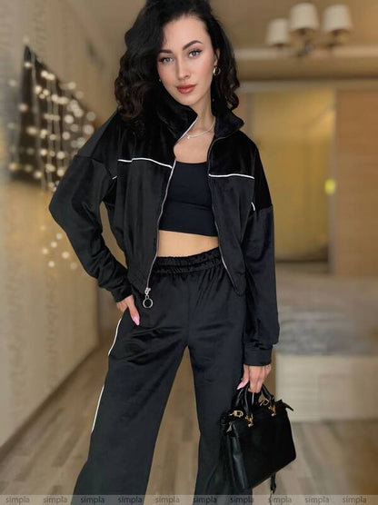 Woman in a black outfit holding a handbag in an indoor setting