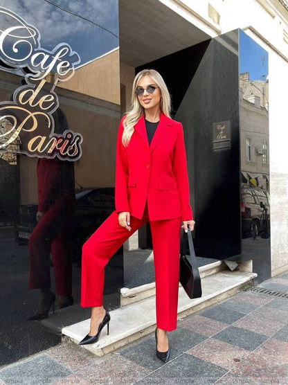 Woman in a red suit standing outside a building with 'Cafe de Paris' sign.