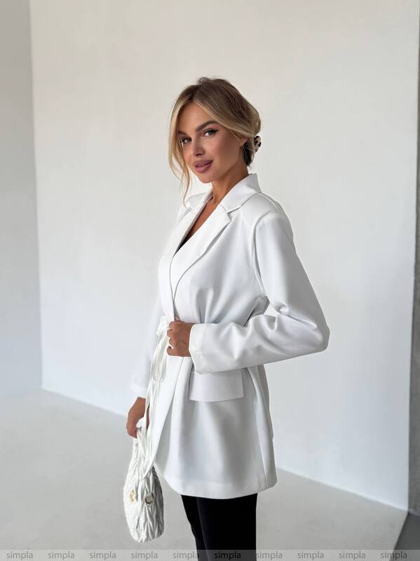 Woman wearing a white blazer against a plain background