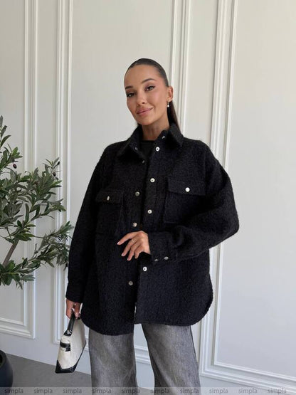 Person wearing a black coat in a minimal indoor setting