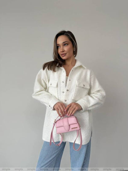 Woman holding a pink handbag against a plain background