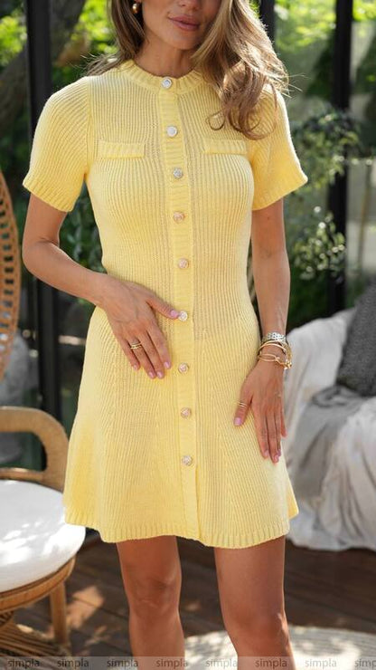 Woman wearing a yellow dress with a button front, standing outdoors.
