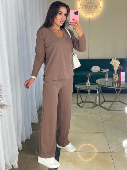 Woman taking a mirror selfie wearing a brown outfit in a living room.