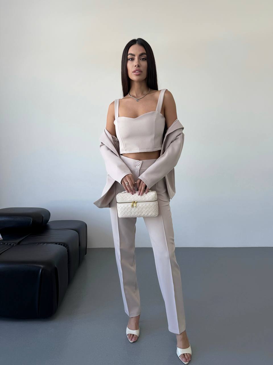 Woman in a stylish outfit with a neutral color palette in an indoor setting.