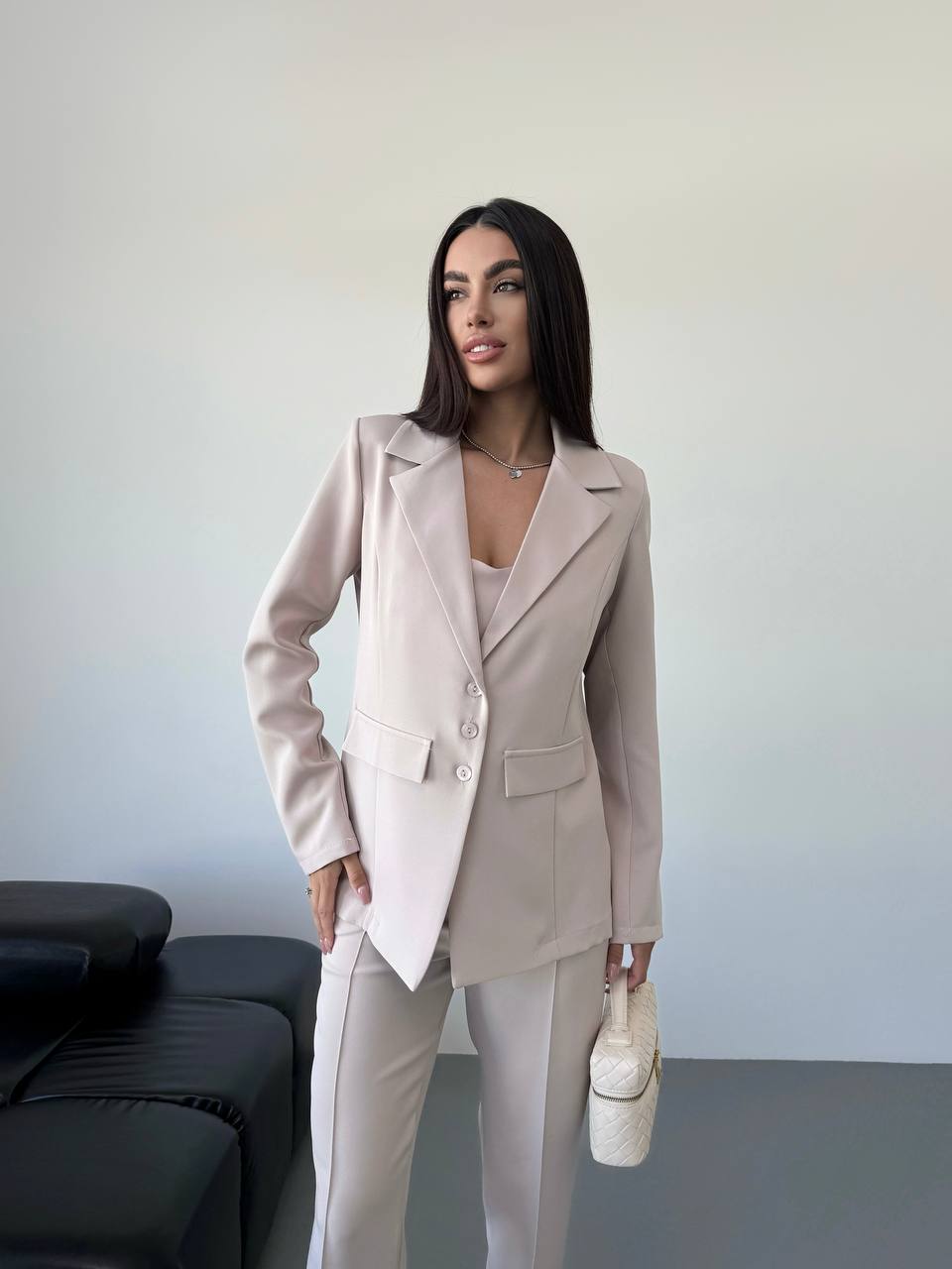 Woman in a beige suit standing against a plain background