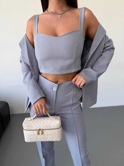 Person wearing a light gray outfit holding a white handbag on a neutral background