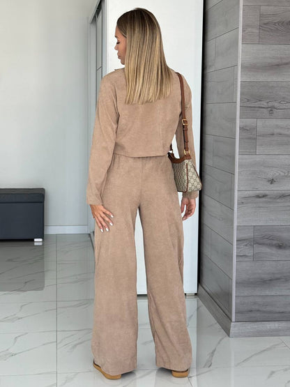 Woman in a beige outfit standing in a modern interior setting.