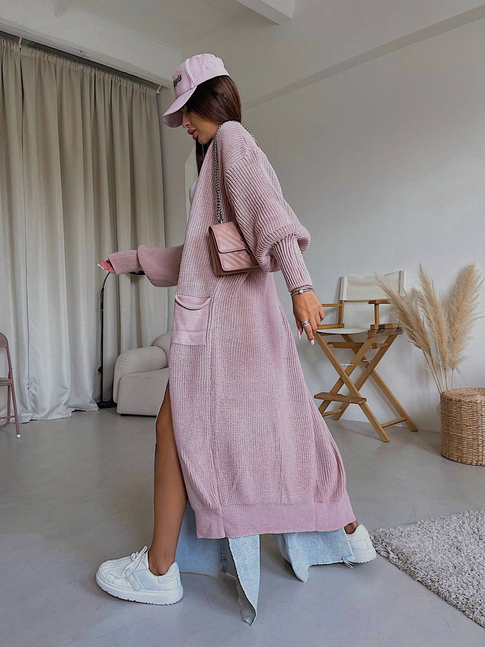 Woman in a pink outfit with a matching cap in a room with neutral decor.