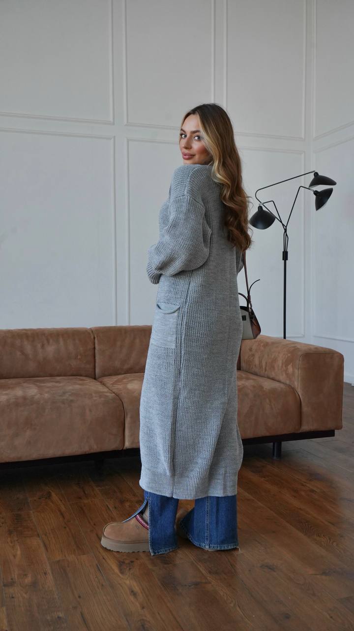 Woman wearing a long gray cardigan in a living room setting.