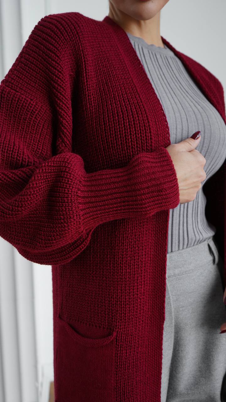 Person wearing a red cardigan over a gray sweater and pants.