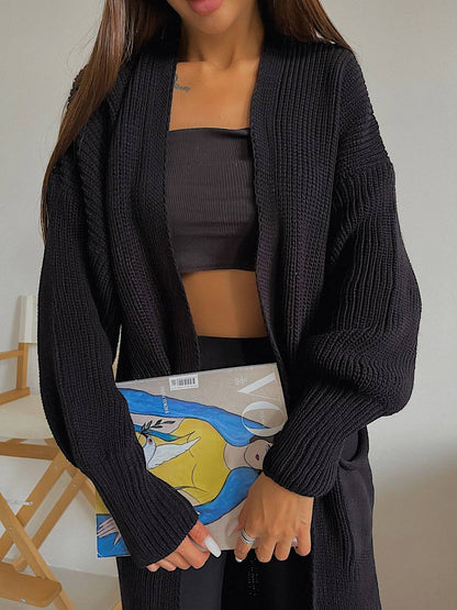 Person wearing a black cardigan over a dark top, holding a colorful book.