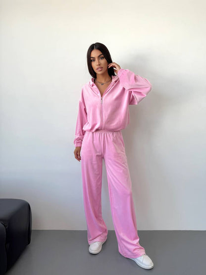 Person wearing a pink tracksuit standing against a plain background