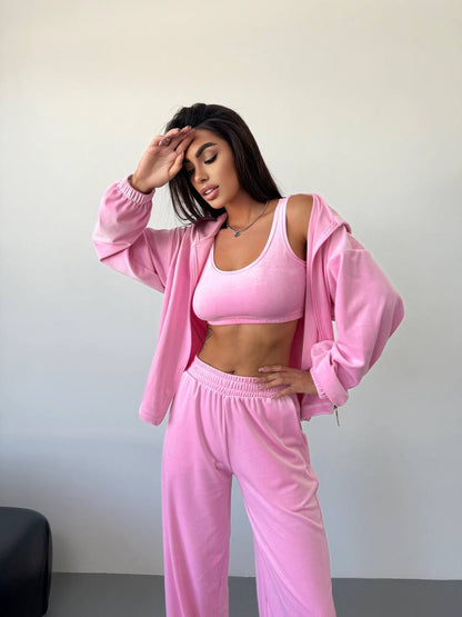 Woman wearing a pink outfit posing against a plain background