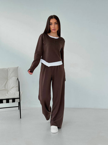 Woman wearing a brown outfit with a white chair in the background