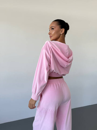 Person wearing a pink tracksuit against a plain background