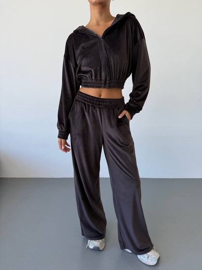 Person wearing a dark brown tracksuit against a plain background