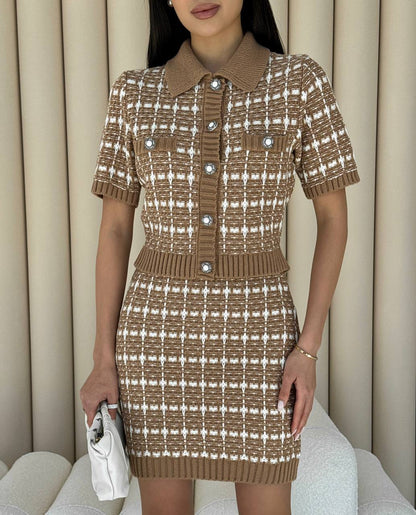 Woman wearing a brown and white checkered dress with a collar, holding a white clutch.