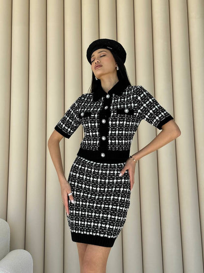 Woman wearing a black and white patterned dress against beige curtains