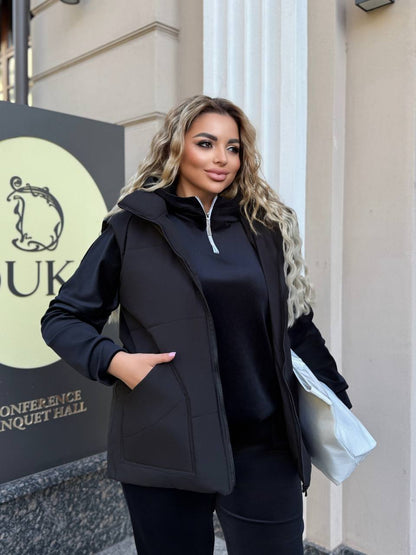 Woman wearing a black coat standing in front of a building with a sign.