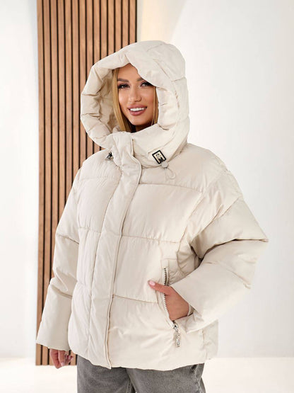 Person wearing a beige puffer jacket with a hood against a white background