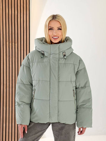 Person wearing a green puffer jacket with a neutral background