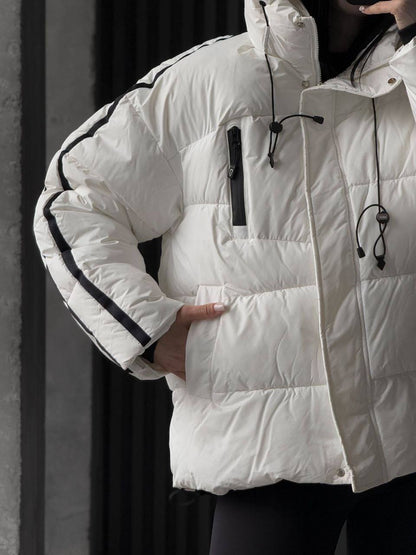 White puffer jacket with black accents worn by a person against a dark background