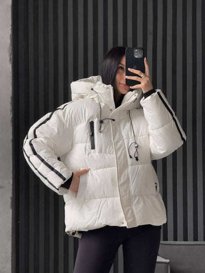 Person wearing a white puffer jacket with black accents, taking a mirror selfie.