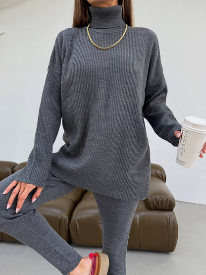 Person wearing a gray sweater and leggings holding a coffee cup indoors.