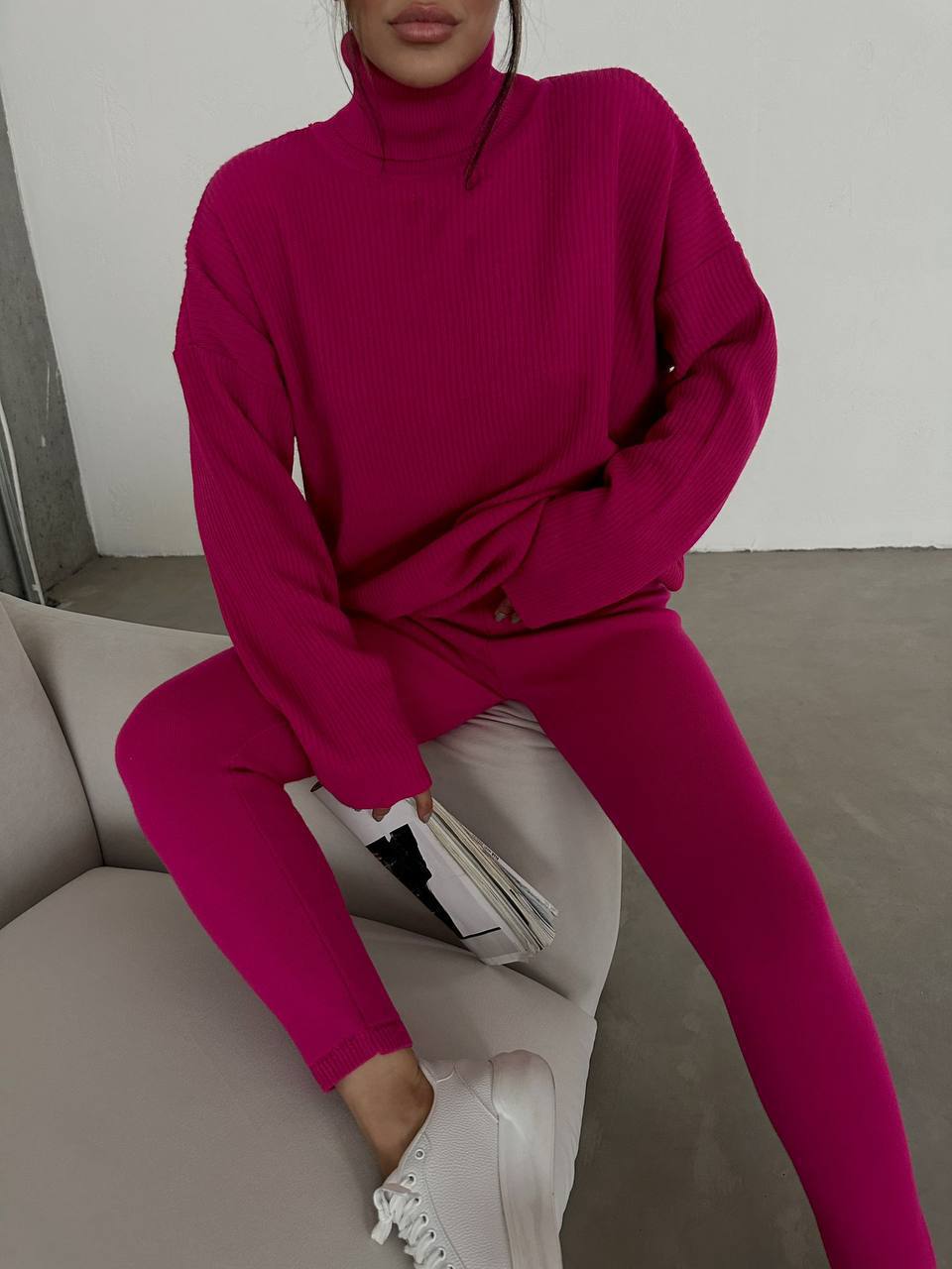 Person wearing a bright pink outfit sitting on a couch.