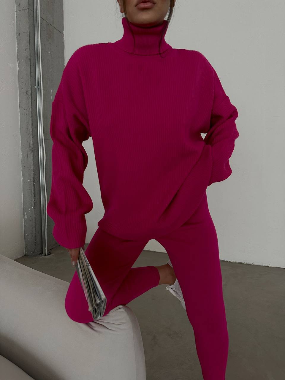 Person wearing a bright pink outfit sitting on a white couch.