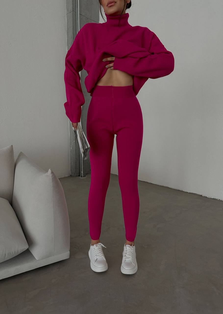 Person wearing a bright pink outfit in a minimalistic room.
