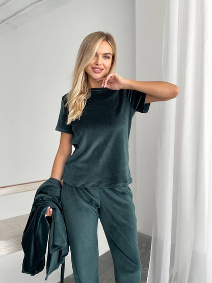 Woman wearing a dark green outfit in a minimalistic room.