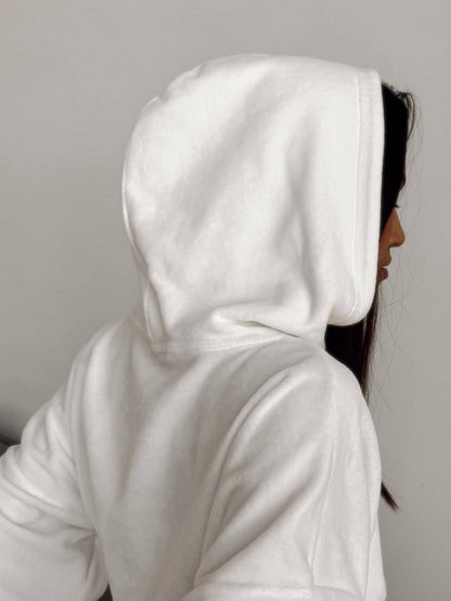 Person wearing a white hoodie against a plain background