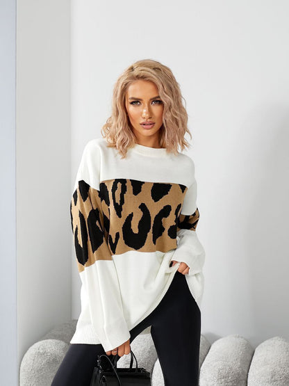 Woman wearing a white sweater with a leopard print design, sitting on a gray couch.