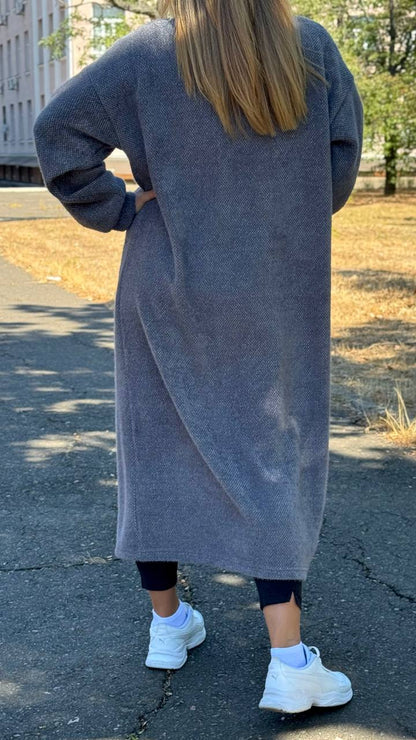 Person wearing a long gray cardigan on a street