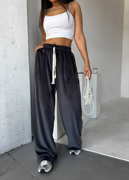 Person wearing a white crop top and black wide-leg pants in an indoor setting.