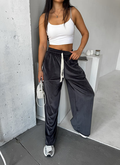 Person wearing a white crop top and black wide-leg pants in an indoor setting.