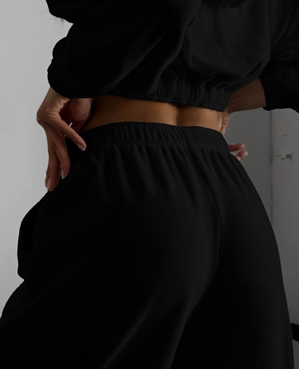 Person wearing black pants and a cropped top against a plain background