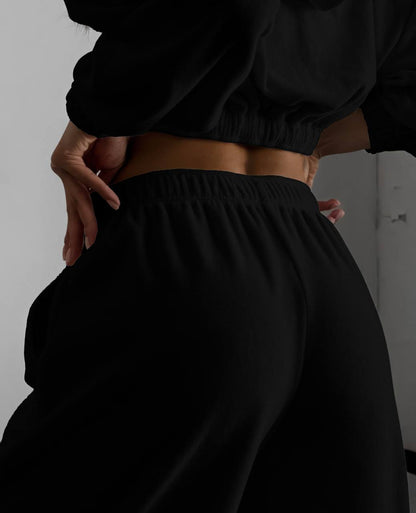 Person wearing black pants and a cropped top against a plain background