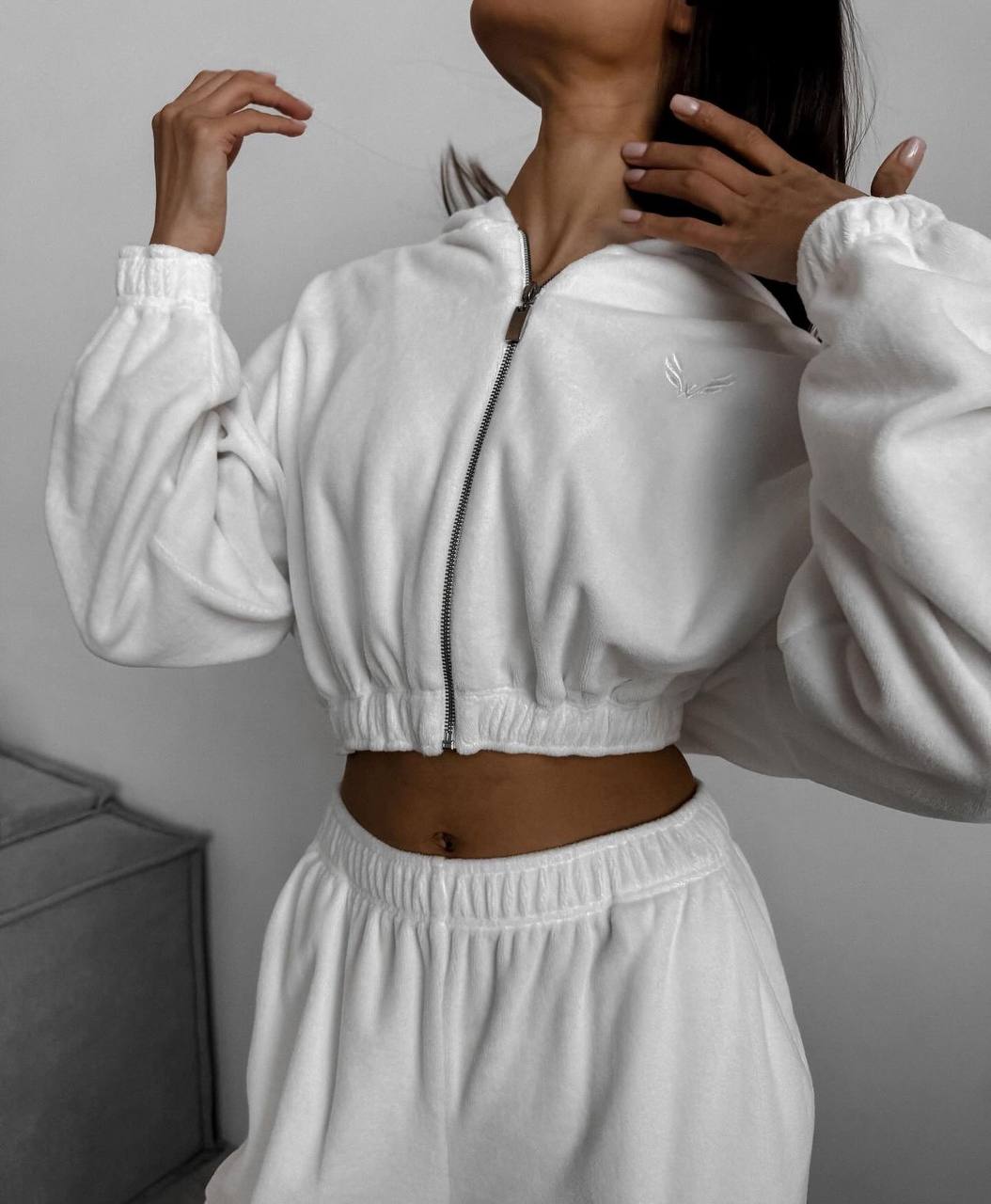 Person wearing a white tracksuit against a neutral background