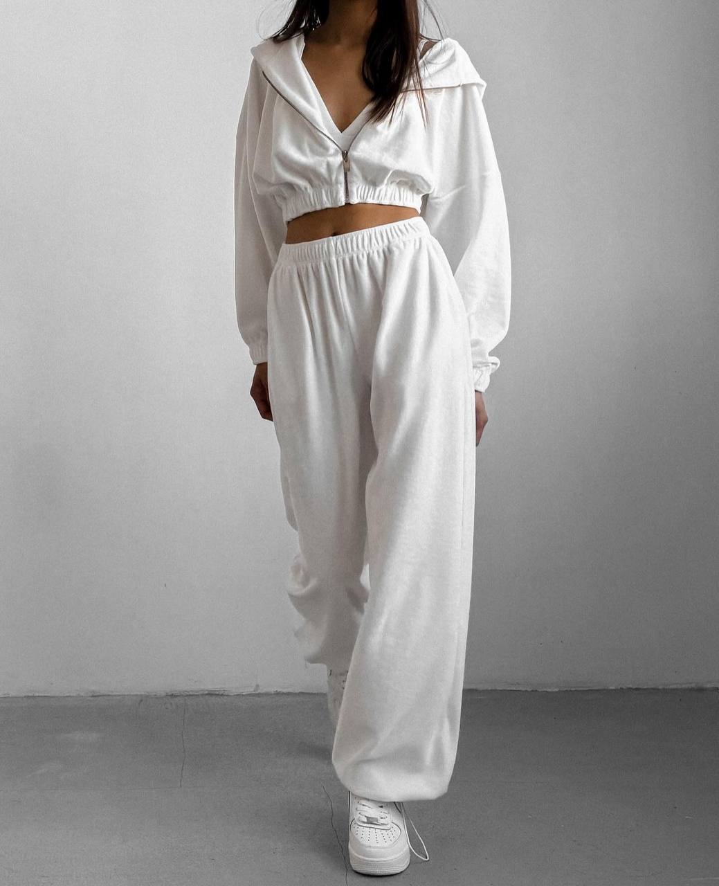 Person wearing a white outfit with a hood against a plain background