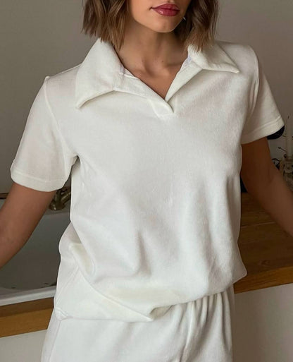 Person wearing a white polo shirt and pants indoors.