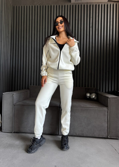 Woman in a white tracksuit standing in a modern interior setting
