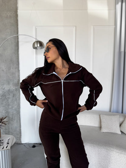 Person wearing a brown tracksuit in a modern room.