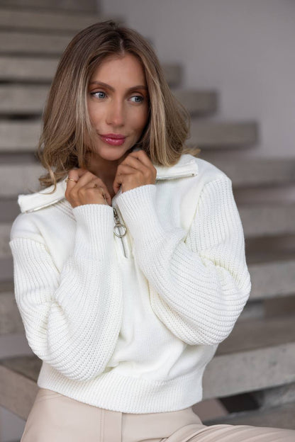 Woman wearing a white sweater standing on a staircase.