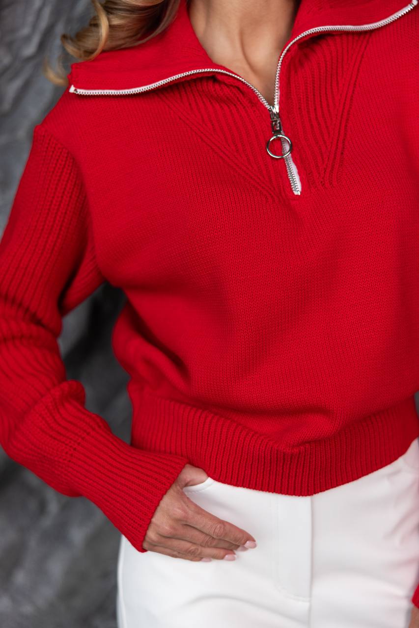Red sweater with a zipper detail worn by a person, blurred background