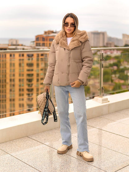 Woman wearing a beige puffer jacket with fur hood on a rooftop with cityscape background