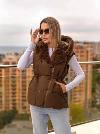 Woman wearing a brown fur-lined vest on a rooftop with cityscape background