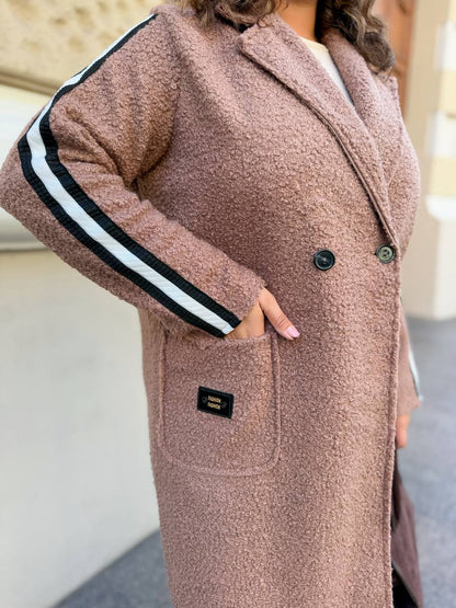 Person wearing a long, brown coat with white stripes on the sleeves.